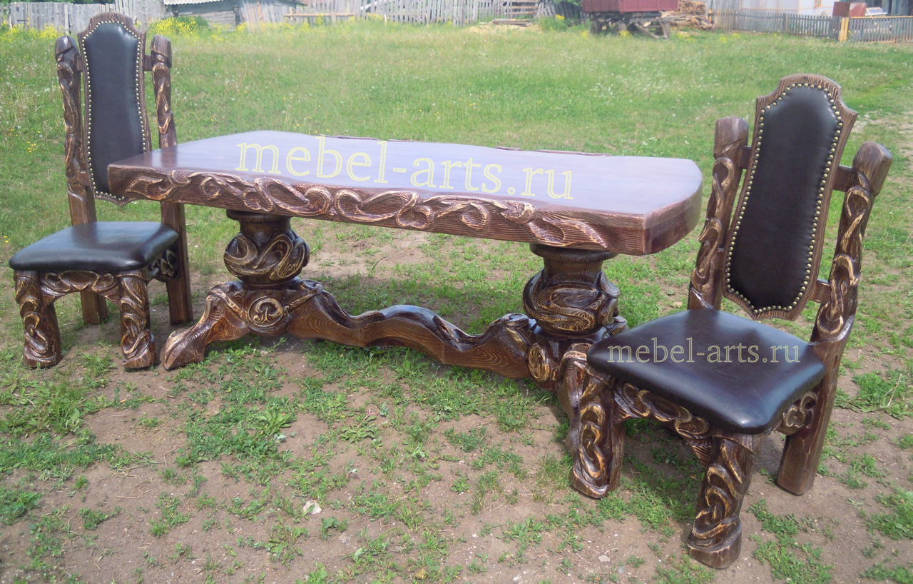 Резной стол на двух массивных ножках. Стулья резные с кожаной обивкой.